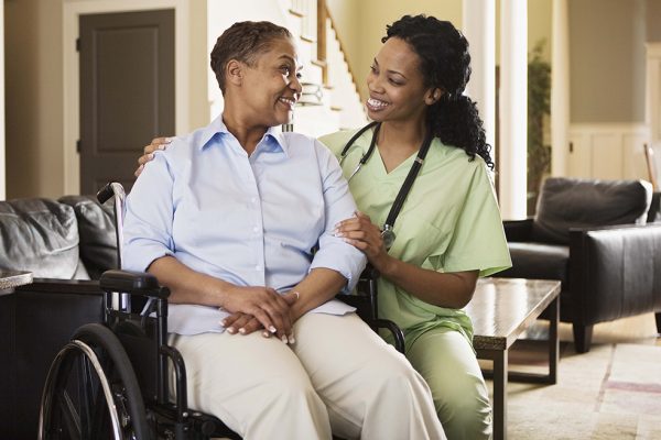 Nurse with woman in wheelchair at home